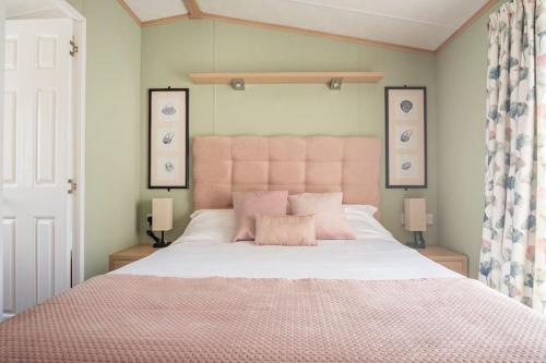 Lytchett MinsterThe Woodlark Lodge at Rockley Park的一间卧室配有一张带粉红色床头板的大床