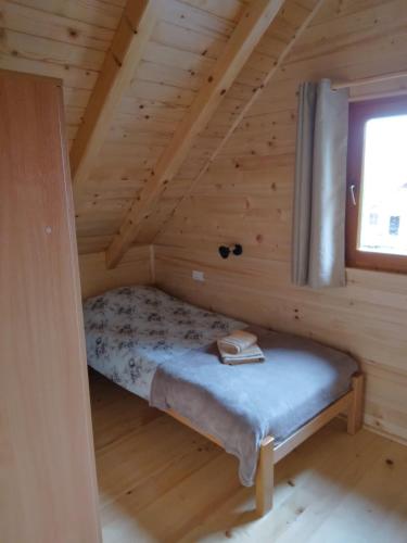 新瓦罗什Brvnara Srna Zlatar的小木屋内的一张小床,设有窗户