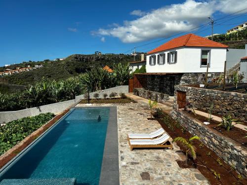 加乌拉CASAS DO LARANJO- Cottages & Infinity Pool的一个带2把躺椅的游泳池以及1栋房子