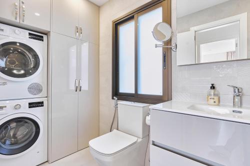 阿德耶WINDSOR OCEAN PEARL APARTMENT的白色的浴室设有洗衣机和水槽。