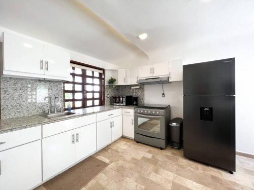 坎昆Beautiful Jungle House on a strategic location的厨房配有白色橱柜和黑色冰箱。