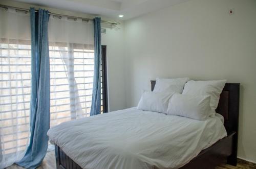 卢萨卡Nsunge Nsunge Farm and Natural Resort的卧室内的一张带白色床单和蓝色窗帘的床