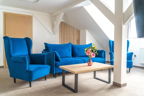 什切尔克阿尔品酒店的客厅配有蓝色的椅子和桌子