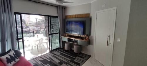 瓜鲁雅Apartamento Guarujá Astúrias的一间带电视和大窗户的客厅