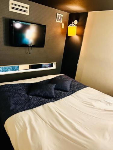 横滨ホテル CROWN MOTEL的配有一张床和一台平面电视的酒店客房