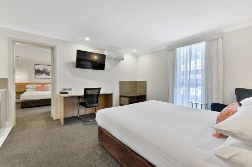 奥兰治卡鲁拉中央汽车旅馆的酒店客房带一张床、一张书桌和一面镜子