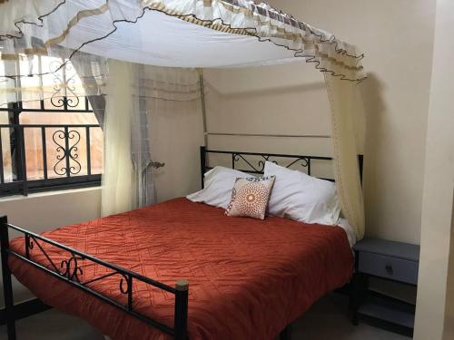 恩德培Amazing lake Victoria Villa, Entebbe的一间卧室配有一张天蓬床和窗户