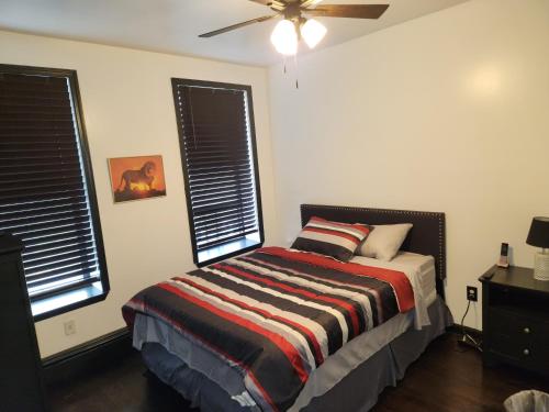 布鲁克林Spacious 3br, 2b的一间卧室配有一张带条纹毯子的床和两个窗户
