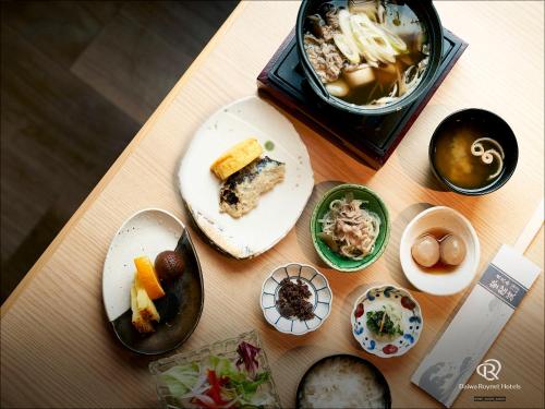 山形市Daiwa Roynet Hotel Yamagata Ekimae的餐桌上放有食物盘子和一盒食物