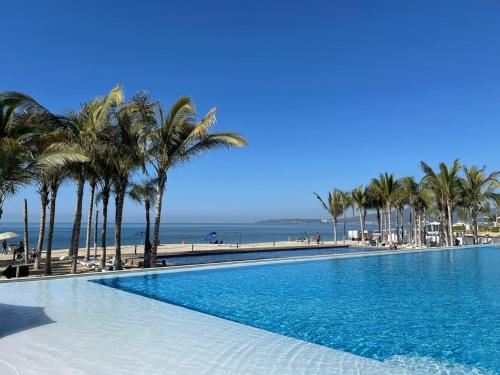 布塞里亚斯Aria Ocean Pacific的棕榈树海滩旁的大型游泳池