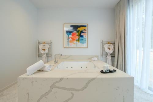 赫本温泉Hepburn Springs Escape的白色的浴室设有浴缸和墙上的绘画作品