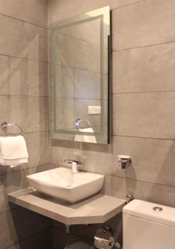 金沙萨Ixoras Hotel Lemba的一间带水槽、卫生间和镜子的浴室