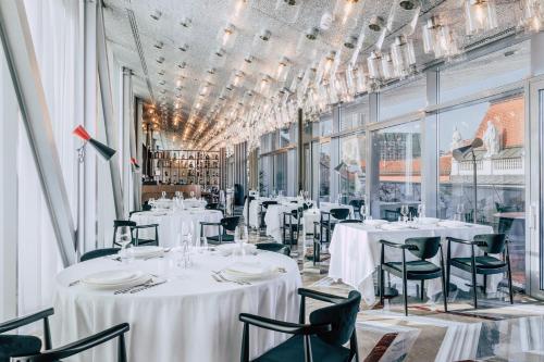 萨格勒布Met Boutique Hotel的餐厅设有白色的桌椅和窗户。