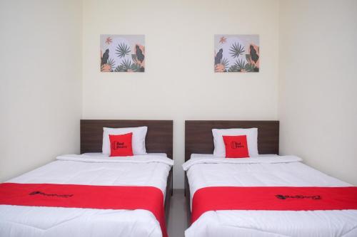 Kalibanteng-kidulRedDoorz near Kawasan Bandara Ahmad Yani Semarang 2的配有红色和白色床单的客房内的两张床