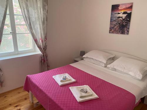 蒂瓦特Apartment Lana的一间卧室配有粉红色的床,上面有两个盘子
