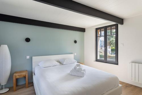 滨海圣布里阿克La Fleur du Moulin - Charmante maison avec jardin proche plage的卧室设有一张白色大床和一扇窗户。