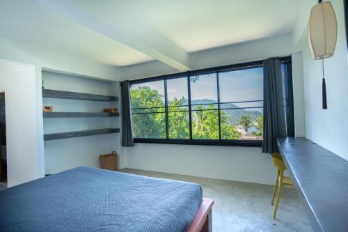 涛岛Banana Villa Koh Tao的一间卧室设有蓝色的床和大窗户