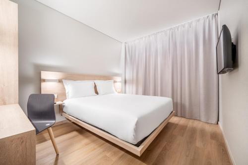 里斯本Moov Hotel Lisboa Oriente的卧室配有白色的床和电视