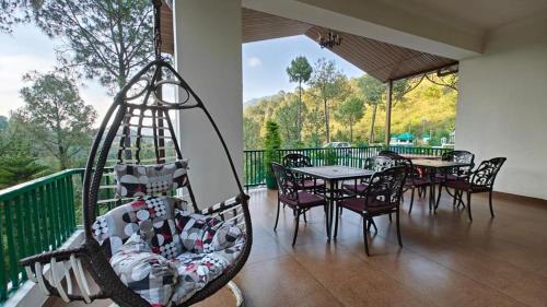 卡绍利Pineland Resorts & Chalets Kasauli的门廊配有桌椅和秋千