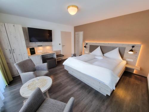 弗罗伊登施塔特瓦尔德苏赫兰德豪斯酒店的卧室配有一张白色大床和两把椅子