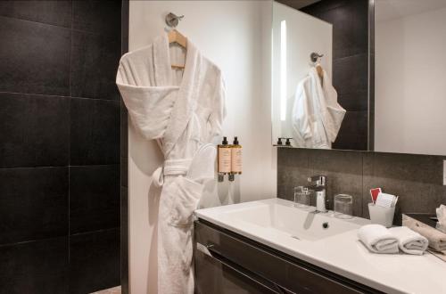 格里尼昂La Ferme Chapouton - Teritoria的浴室设有水槽,墙上挂着白色的长袍