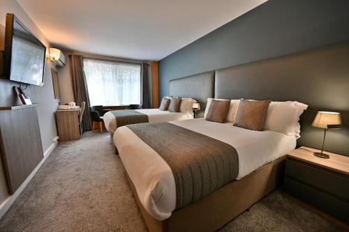 伦敦肯辛顿苑酒店 - 伯爵府 的酒店客房设有两张床和电视。