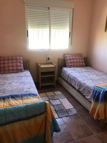 ÚbedaVilla Vida的一间卧室设有两张床和一张桌子及窗户