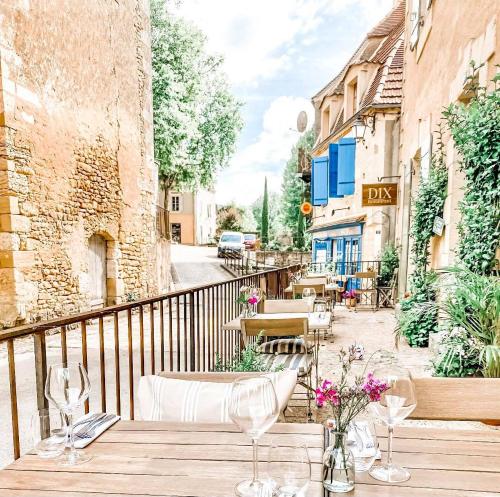Saint-AlvèreDIX Restaurant & Chambres d'hotes的阳台上配有带椅子和鲜花的木桌
