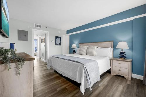 默特尔比奇Direct OCEANFRONT- King Bedroom- AMAZING VIEWS/Pools/Hot Tubs/Beach Access/Golf的一间卧室设有一张蓝色墙壁的大床
