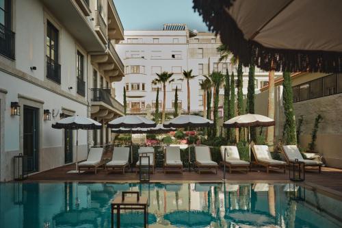波尔图GA Palace Hotel & Spa, a XIXth-Century Villa的一座带椅子和遮阳伞的游泳池位于一座建筑旁边