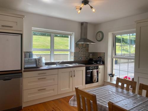 多尼戈尔The Lodge Donegal Town的厨房配有白色橱柜、餐桌和用餐室
