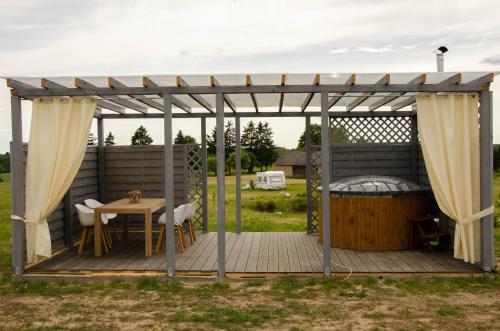 FilipówDomki na Wzgórzu - Rospuda - Domek z sauną的木甲板配有桌子和凉亭