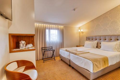 巴塔拉Hotel Lis Batalha的配有一张床和一把椅子的酒店客房