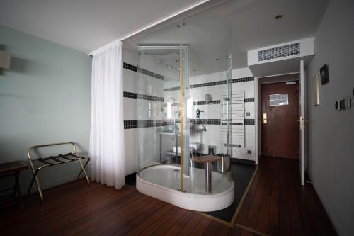 勒阿弗尔LOGIS HOTEL - La Petite Rade的一间带玻璃淋浴和浴缸的浴室