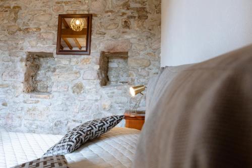 阿西西Rustic House, con patio e giardino, Assisi centro的一间卧室设有石墙、一张床和一盏灯