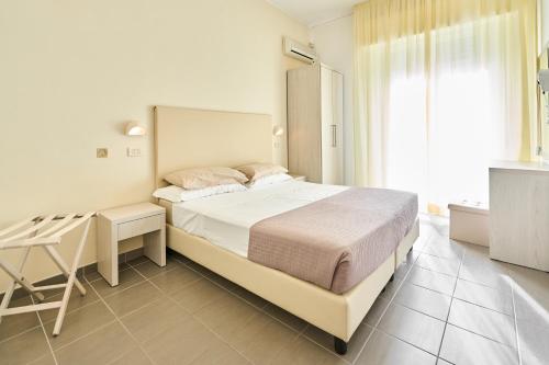 里米尼Hotel Villa Perazzini的一间卧室配有一张床、一张书桌和一个窗户。