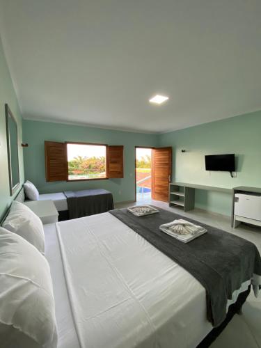 伊卡普伊Pousada Maanain的卧室配有一张白色大床和一台平面电视。