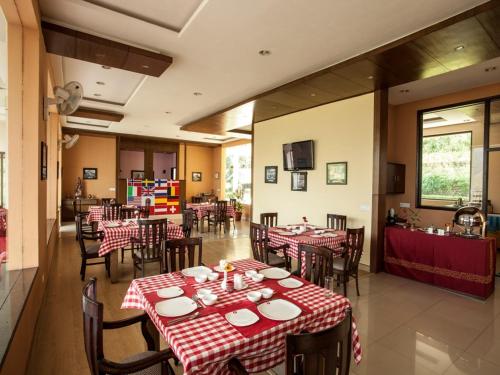JūngaFlag House Resort的餐厅设有桌椅,配有红色和白色的桌布