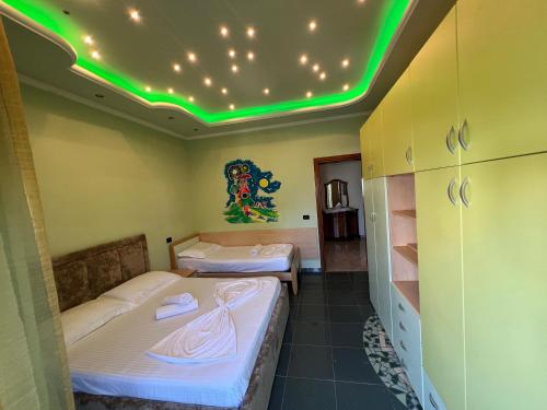 都拉斯Green Garden Villa的天花板上设有绿灯的客房内的两张床