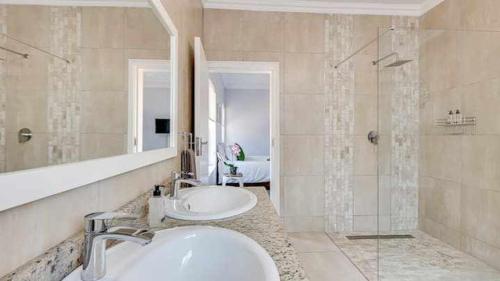 约翰内斯堡East Prestige lodge的浴室设有2个水槽、镜子和淋浴。