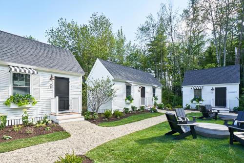 肯纳邦克Wanderer Cottages的后院设有两座白色房屋和长凳
