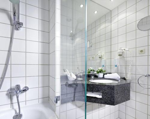 莱比锡萨克森公园酒店的白色瓷砖浴室设有水槽和淋浴