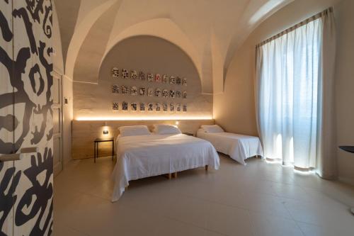 加利波利Palazzo Vergine - by Inside Salento的酒店客房设有两张床和窗户。