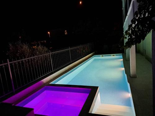 维尼斯切Apartments Neli的游泳池晚上有紫色灯光