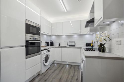 邓巴顿Little Gleddoch的厨房配有白色橱柜、洗衣机和烘干机