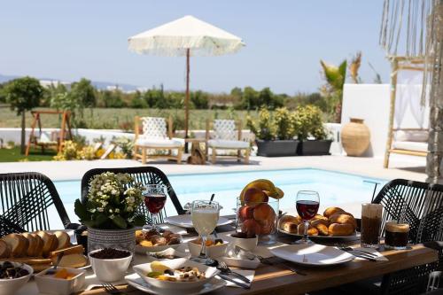 布拉卡OLIVES seaside villas (4elies)的游泳池旁的餐桌上摆放着食物和葡萄酒