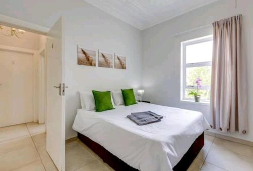 约翰内斯堡East Prestige lodge的白色卧室配有一张带绿色枕头的大床