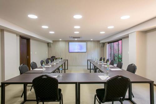 亚松森拉斯洛马斯卡萨酒店的一间会议室,配有长桌子和椅子以及屏幕