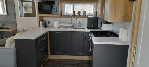 爱丁堡Luxury spacious family caravan的厨房配有蓝色橱柜和炉灶烤箱。