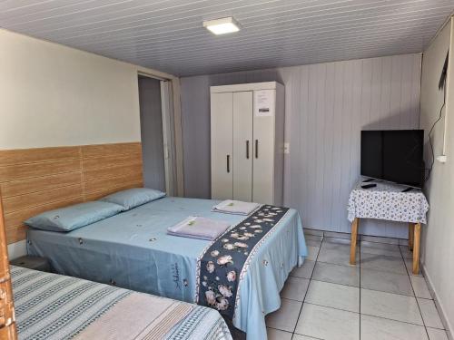 伊瓜苏Suite Cardoso的一间带两张床和电视的小卧室